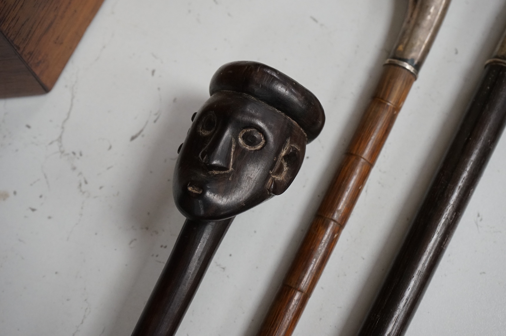 Two silver mounted walking sticks and a tribal carved ebony walking stick, longest 93cm